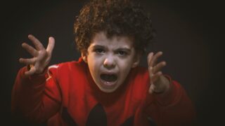 A young child expressing strong emotions during a studio portrait shoot.